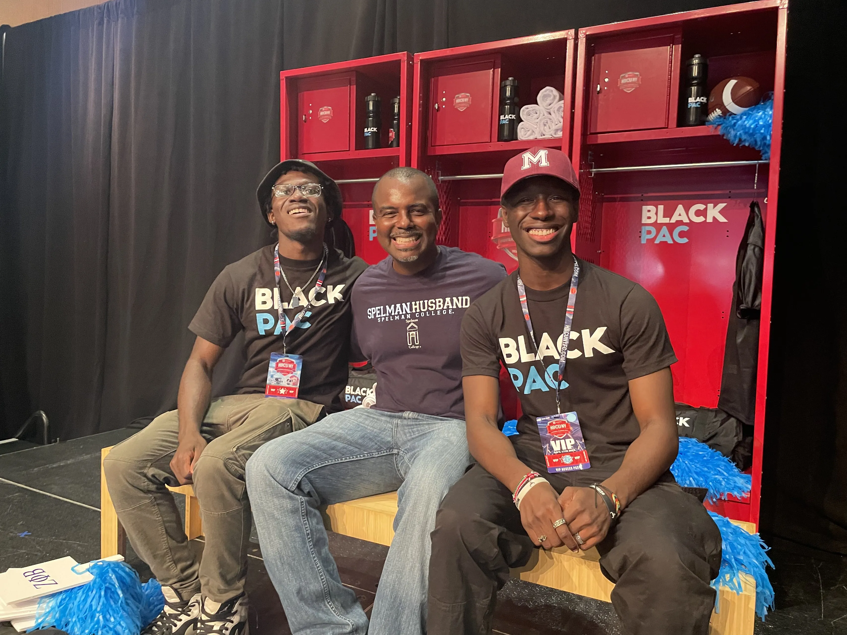 Three young men in BlackPAC shirts seated in a locker room