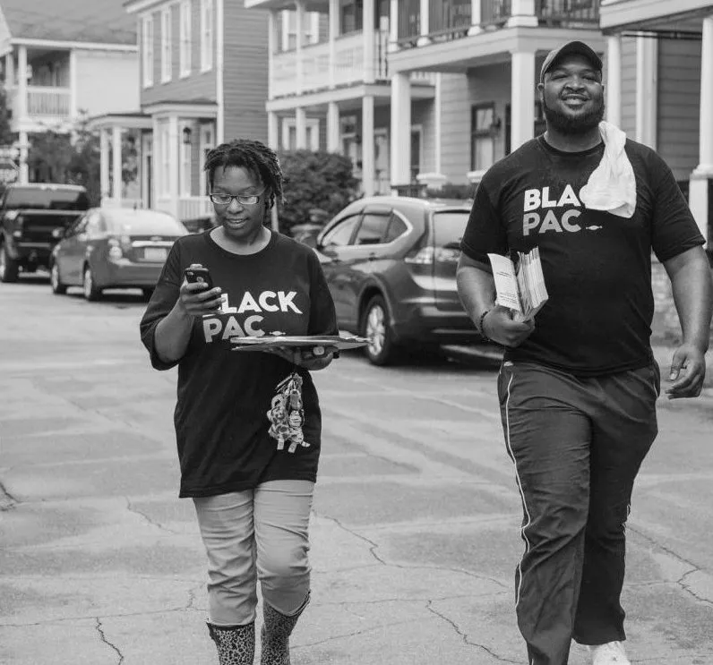 Two BlackPAC canvassers walking down a residential street with voter guides
