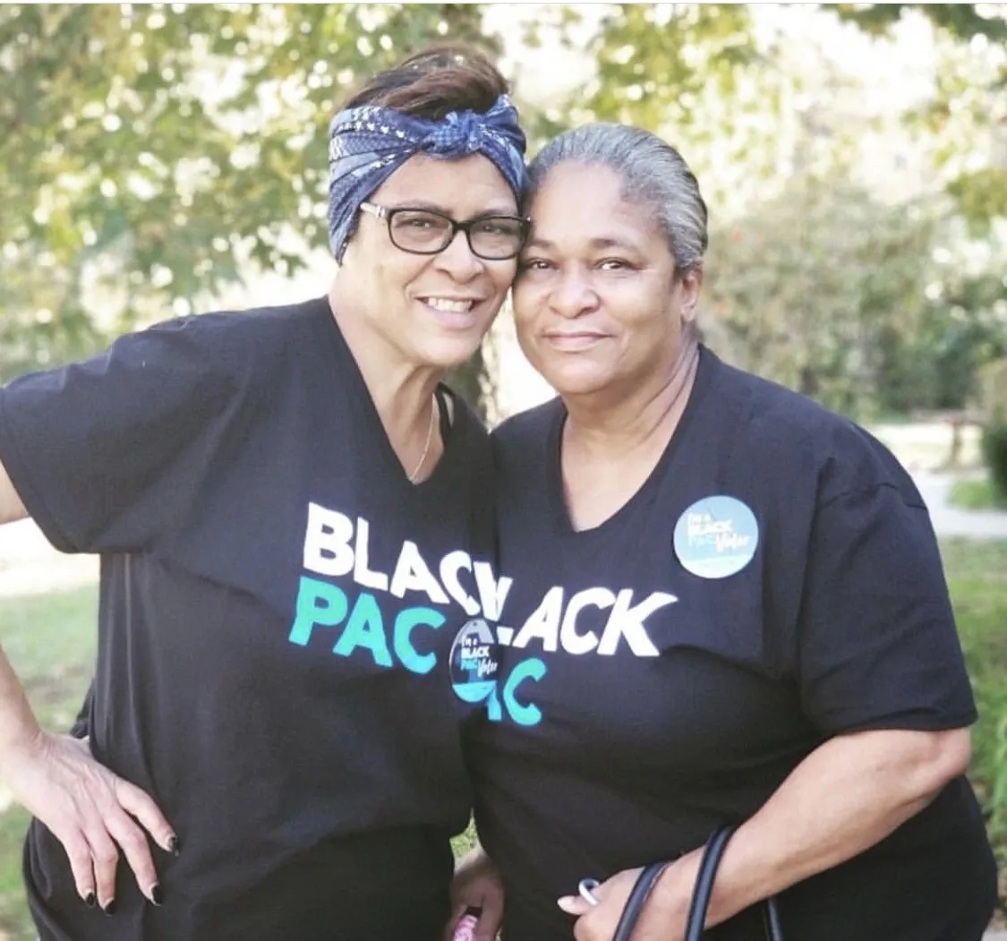 Two women in BlackPAC shirts embracing outdoors